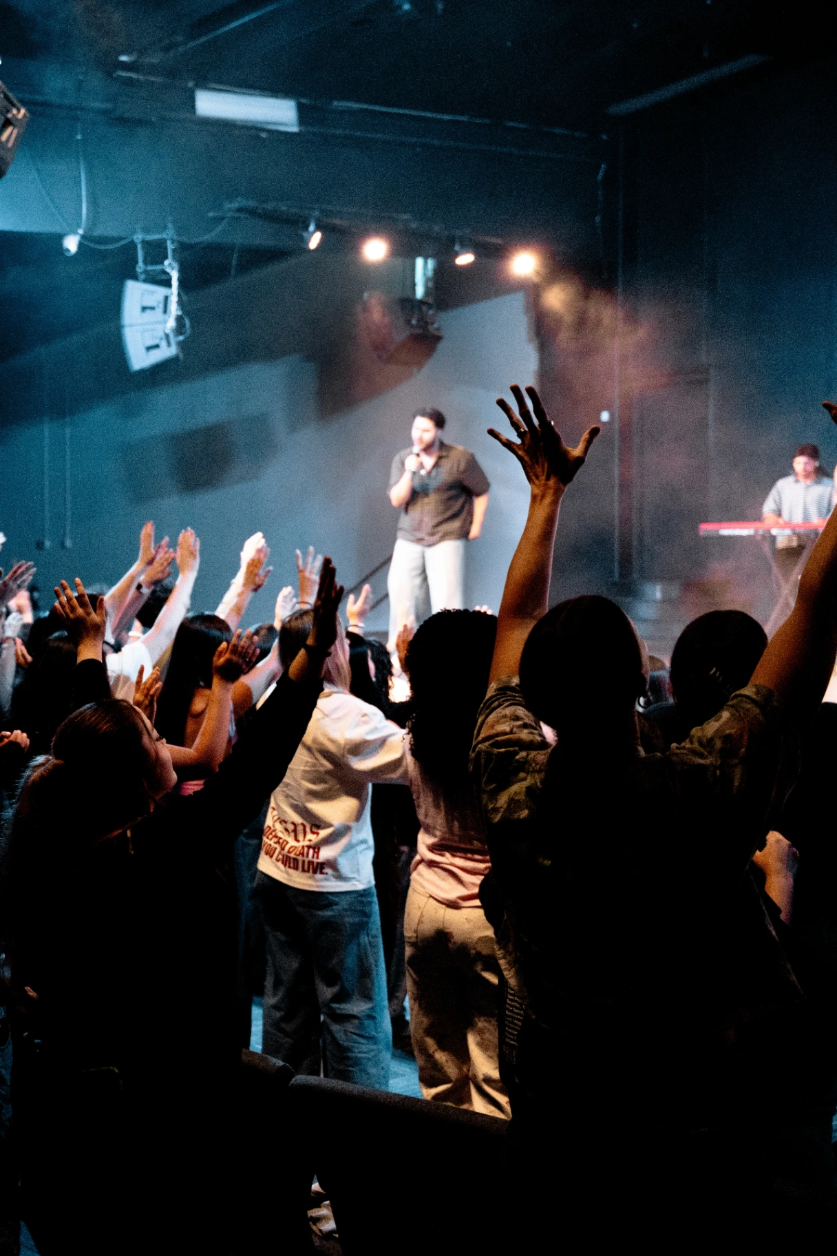 Worship leader and crowd with hands raised